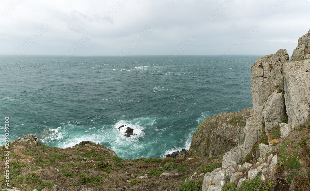 wild rocky coast with cliffs and green meadows under an overcast sky