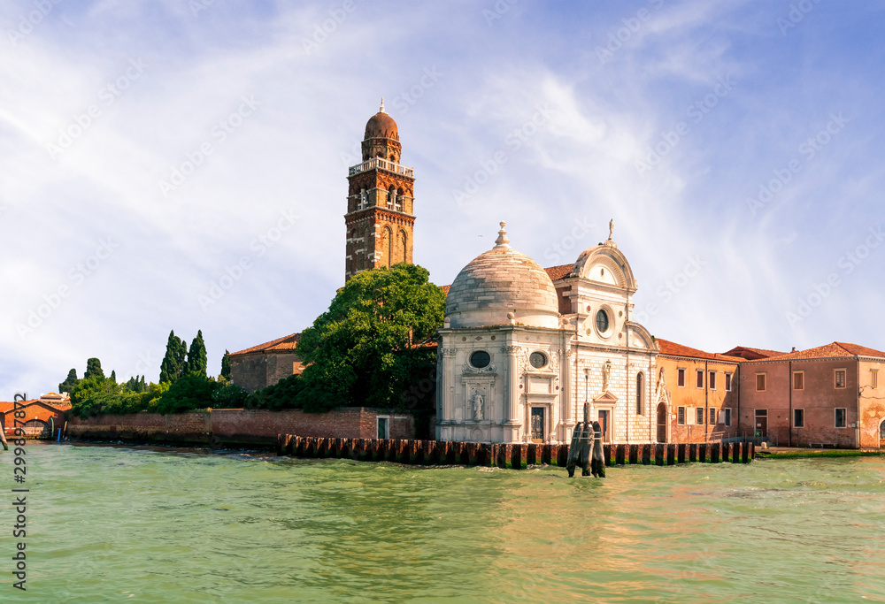picturesque view at a tower from sea during a sunset , old domes and green trees with beautiful evening sky on a background , venetian landscape