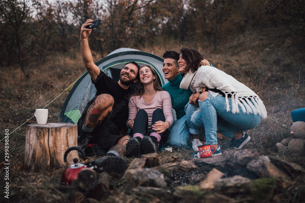 Young friends laughing, taking selfie,hanging out at campsite