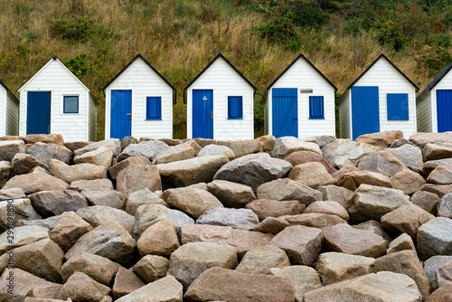 row of small wooden beach cottages on the rocky Normandy coast