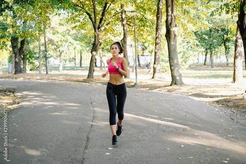 Young portive woman running on walkway in the park