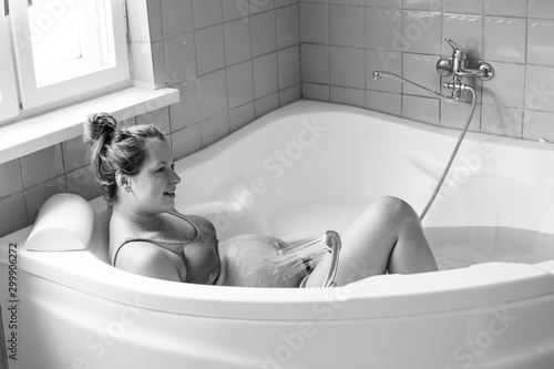 Pregnant woman in labour, labor, during childbirth, giving birth, birthing pool, water bath. Water birth.