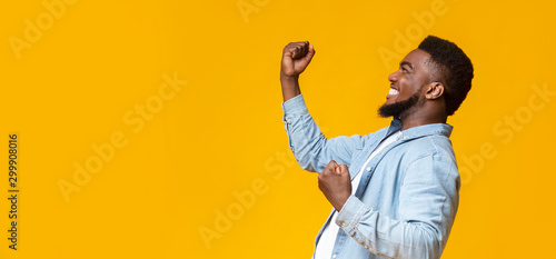 Happy black guy raising fists in the air, celebrating success photo