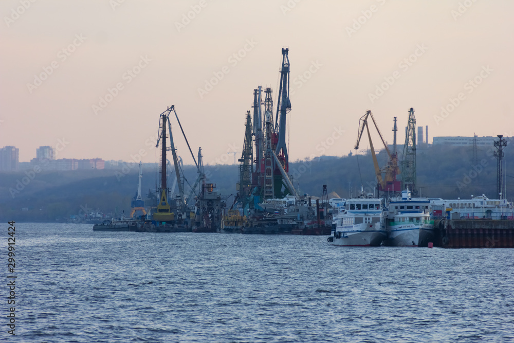 View on industrial landscape with cranes in a port. Cranes are near a river to load and unload cargo vessels.A place of a real business and industry.