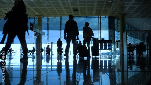 International airport with business people pulling trolley bags arriving and departing terminal tourists travelling and walking in lobby with big windows and blue sky 4k footage