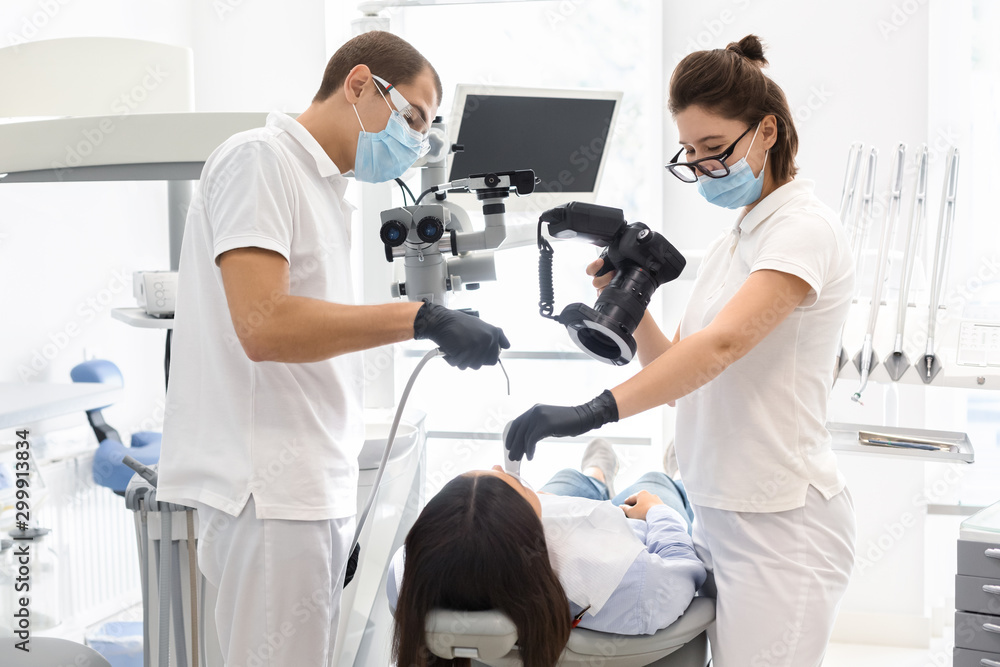Skillful dentists taking photo of patient teeth after treatment complete Skillful dentists taking photo of patient teeth after treatment complete