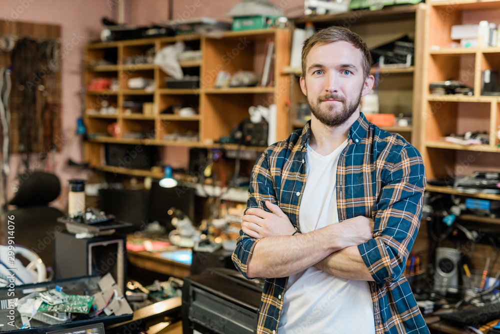 Young professional repairman of broken gadgets crossing arms by chest Young professional repairman of broken gadgets crossing arms by chest