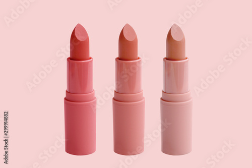 set of matte lipstick on a delicate pink background, red, raspberry, pink, coral, peach color, close-up, the concept of decorative cosmetics photo