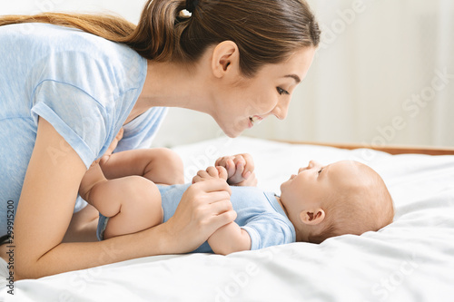 Young mother playing with her cute newborn baby in bed