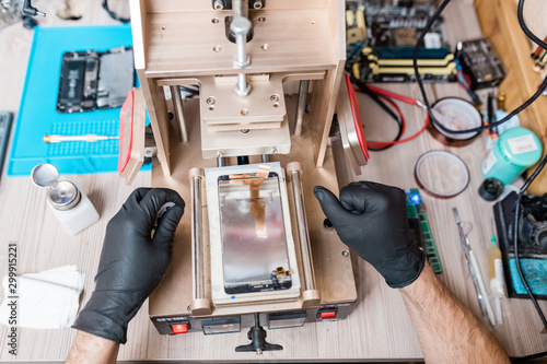 Billede på lærred Gloved hands of professional repairman using equipment for gadget repair