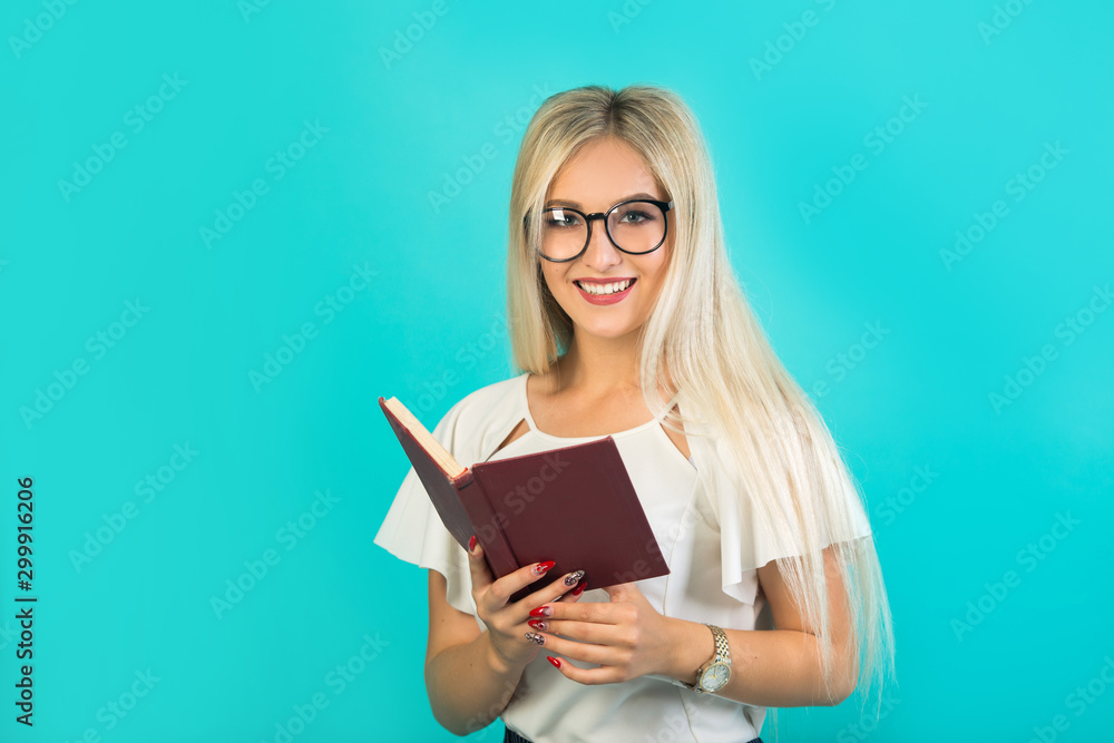 beautiful young woman in glasses holds a book on a blue background beautiful young woman in glasses holds a book on a blue background