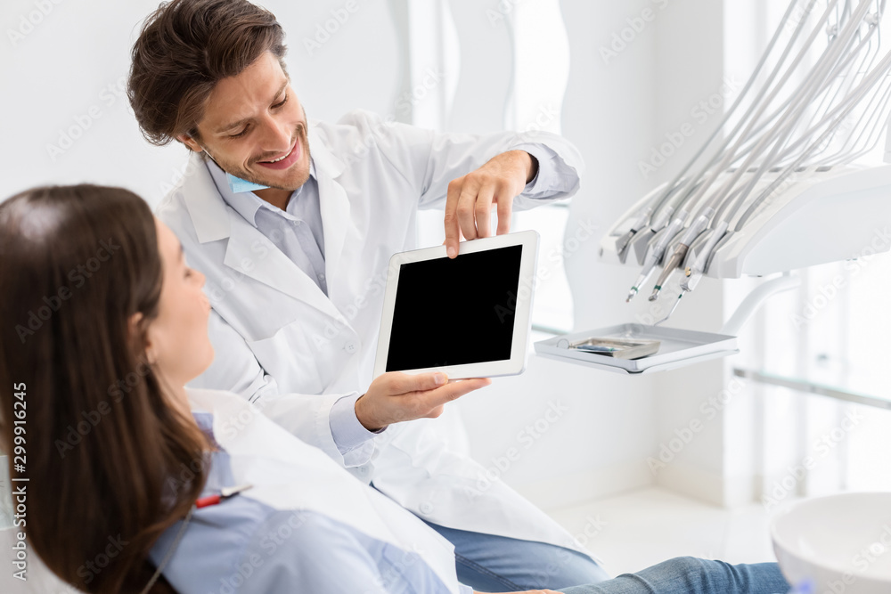 Handsome dentist showing blank digital tablet screen Handsome dentist showing blank digital tablet screen