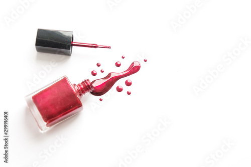 Spilled nail Polish and bottle on white background. Drops of liquid nail Polish.