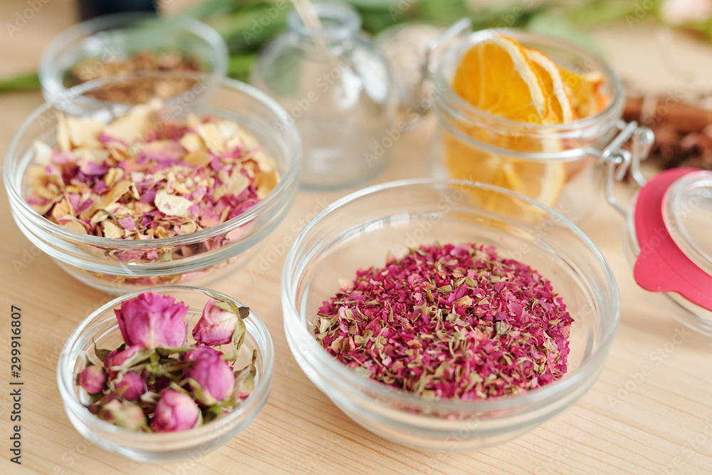 Three bowls with dry rose petals and rosebuds and small jar with orange slices Three bowls with dry rose petals and rosebuds and small jar with orange slices
