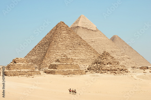 Tourists on camels are seeing Khufu  Khafre  Menkaure and pyramids of Queens