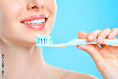 Young beautiful woman is engaged in cleaning teeth. Beautiful smile healthy white teeth. A girl holds a toothbrush. The concept of oral hygiene. Promotional image for a stomatology, dental clinic.