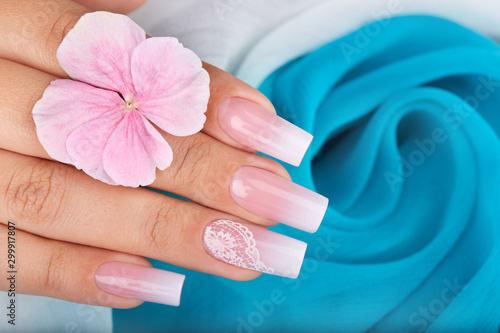 Obraz na plátně Hand with long artificial manicured nails with ombre gradient design in pink and