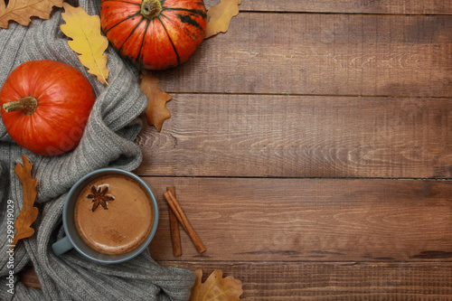 Grey cup of coffee with milk and spices, plaid, yellow oak leaves, orange pumpkins on dark brown wooden table. Autumn drink concept. Fall, pumpkin spicy latte, thanksgiving, top, copy space