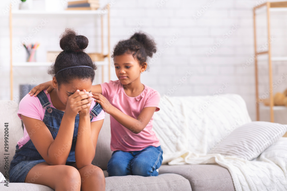 Little african girl comforting her crying teen sister with relationship problems Little african girl comforting her crying teen sister with relationship problems