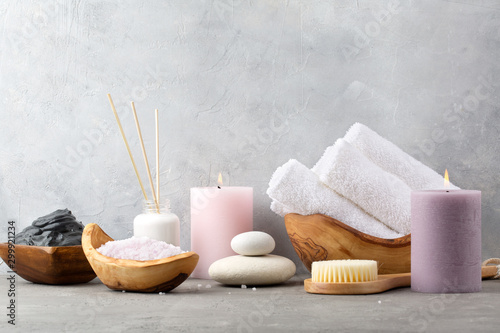 Spa and relax. Candles, bath salt, dead sea mud, stones and brush for body on grey background.