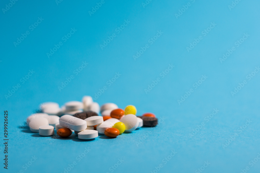 Medical pills in different colors on blue background. Medical pills in different colors on blue background.