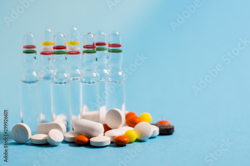 Medical ampules and pills on blue background