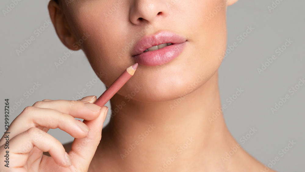 Woman drawing lips with nude pink lipliner