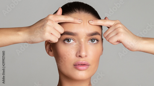 Foto Problem skin. Girl crushing acne on her forehead