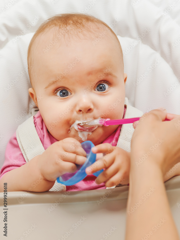 Mother feeding her baby girl with a spoon. Mother feeding her baby girl with a spoon.