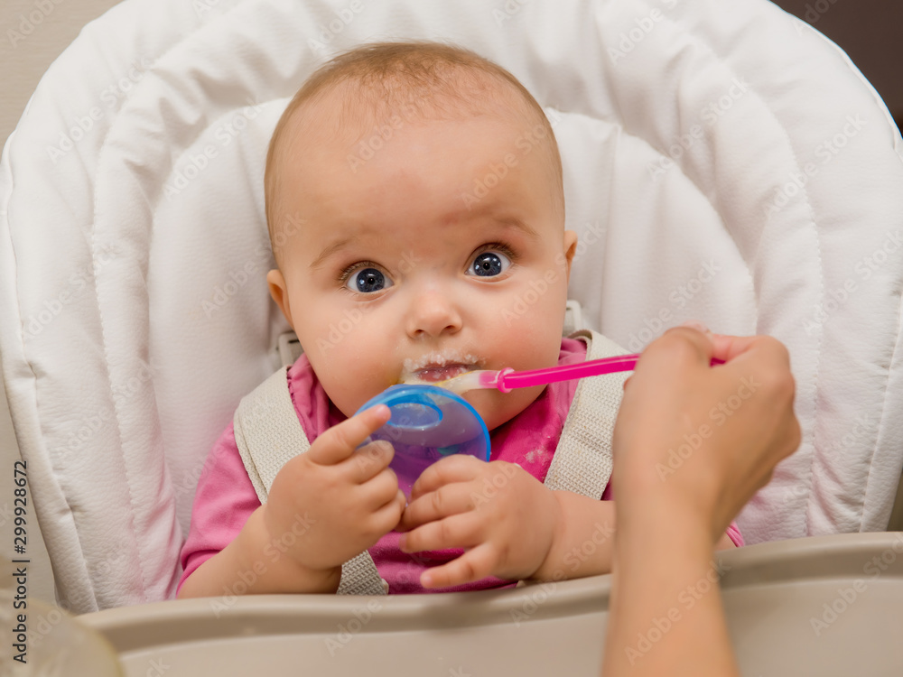 Mother feeding her baby girl with a spoon. Mother feeding her baby girl with a spoon.
