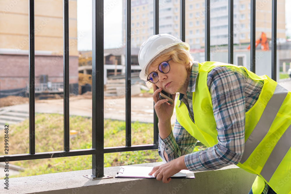 A female builder worker at a construction site works and controls the process. A female builder worker at a construction site works and controls the process.