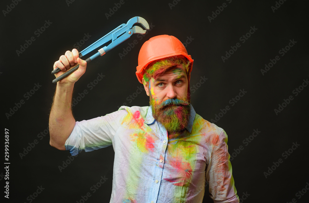 Plumber with Pipe wrench or plumbing spanner. Bearded man in protective helmet with repair tools. Mechanic in work clothes in helmet with adjustable wrench. Repair tools. Workplace. Repair service. Plumber with Pipe wrench or plumbing spanner. Bearded man in protective helmet with repair tools. Mechanic in work clothes in helmet with adjustable wrench. Repair tools. Workplace. Repair service.