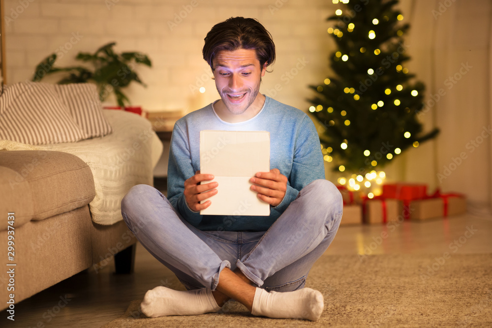 Christmas magic. Joyful guy opening gift box Christmas magic. Joyful guy opening gift box