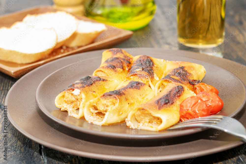 Fototapeta premium Cooked hot stuffed cannelloni for eating on the natural wooden table.