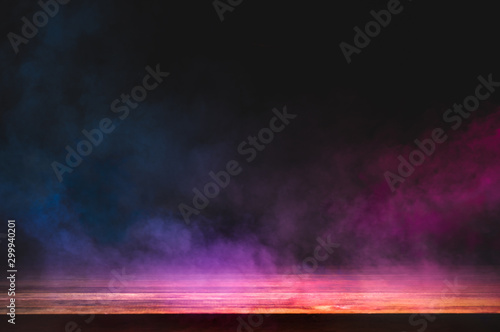 empty wooden table with colorful smoke float up on dark background