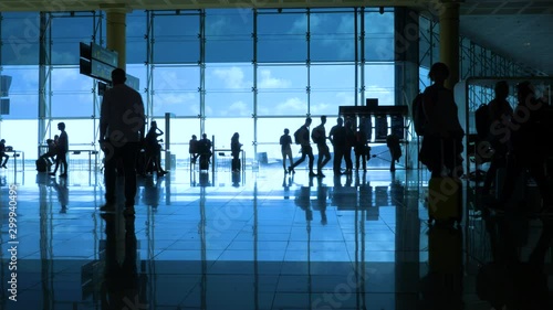 International airport with business people pulling trolley bags arriving and departing terminal tourists travelling and walking in lobby with big windows and blue sky 4k footage