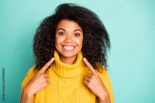 Closeup photo of amazing dark skin curly lady indicating fingers on perfect teeth advising dentist wear yellow knitted pullover isolated blue teal color background