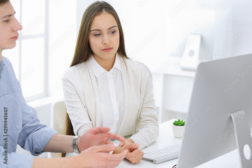 Business woman and man sitting and working with computer in office. Colleagues discussing something at meeting. Corporate teamwork and partnership concepts Business woman and man sitting and working with computer in office. Colleagues discussing something at meeting. Corporate teamwork and partnership concepts