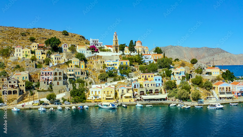 View on Greek sea Symi island harbor port, classical ship yachts, houses on island hills, tourists Aegean Sea bay. Greece islands holidays vacation travel tours from Rhodos island. Greece architecture