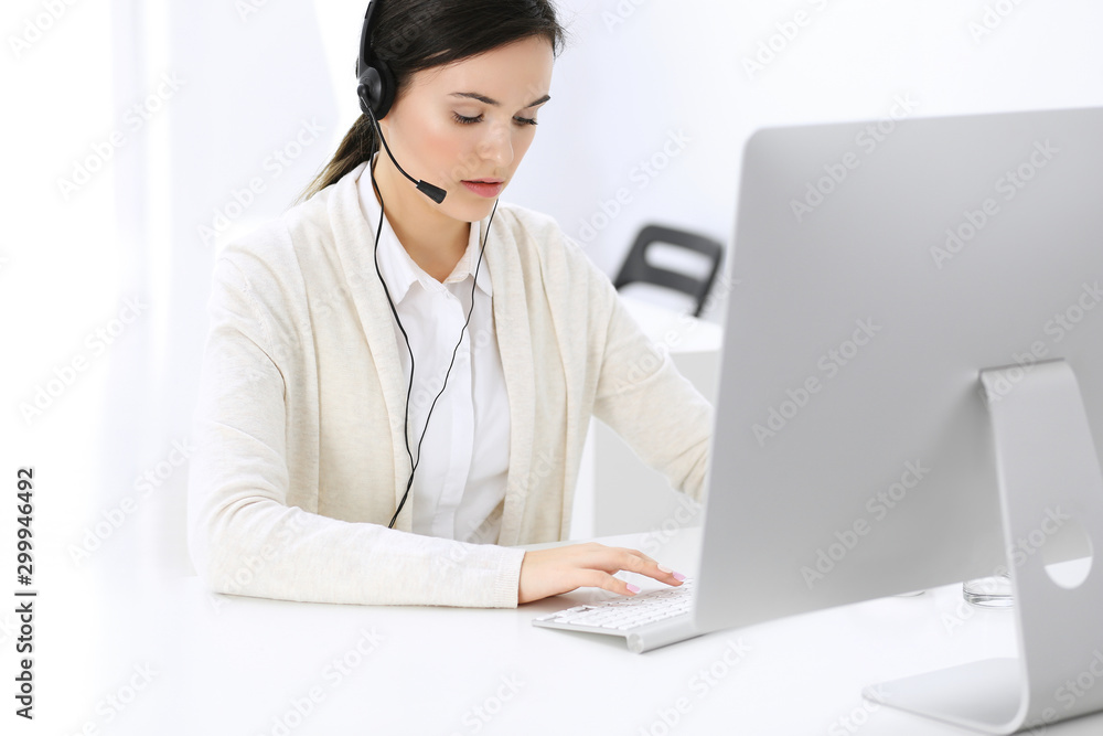 Call center. Beautiful woman receptionist sitting in headset at customer service office. Group of operators at work. Business concept Call center. Beautiful woman receptionist sitting in headset at customer service office. Group of operators at work. Business concept