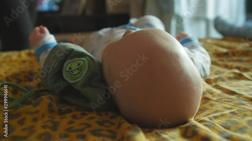 Baby lies on the bed. Mother puts a hat on the baby. Close up shot. photo