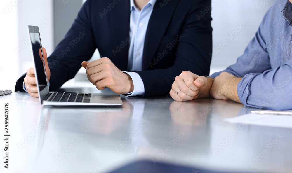 Business people using laptop computer while working together at the desk in modern office. Unknown businessman or male entrepreneur with colleague at workplace. Teamwork and partnership concept Business people using laptop computer while working together at the desk in modern office. Unknown businessman or male entrepreneur with colleague at workplace. Teamwork and partnership concept