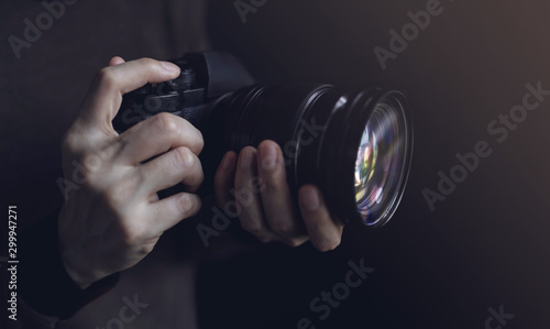 Young Photographer Woman using Camera to Taking Photo. Dark Tone. Selective Focus on Hand photo