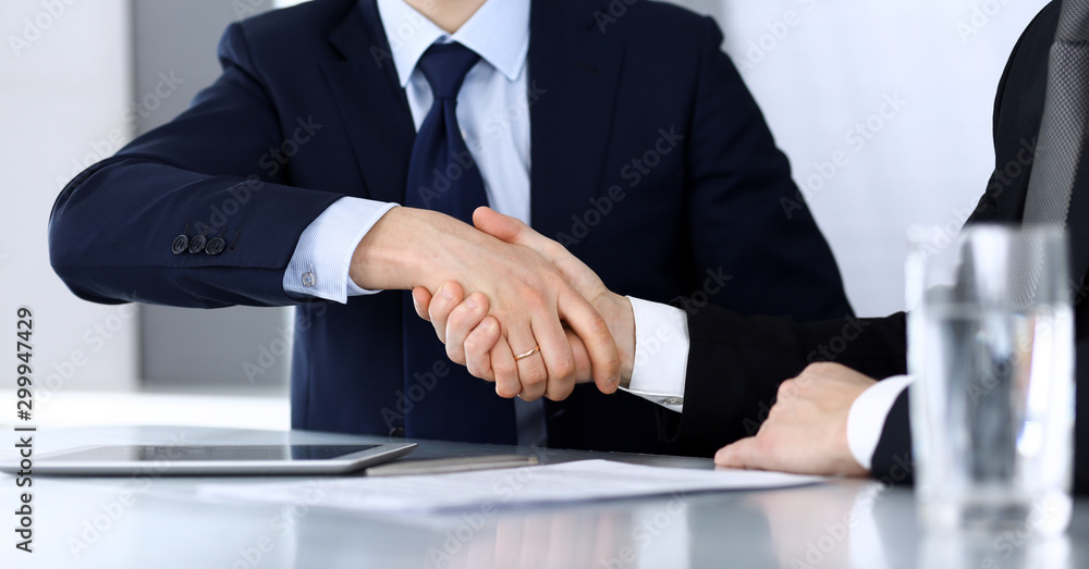 Business people shaking hands after contract signing at the glass desk in modern office. Unknown businessman, male entrepreneur with colleague at meeting or negotiation. Teamwork, partnership and Business people shaking hands after contract signing at the glass desk in modern office. Unknown businessman, male entrepreneur with colleague at meeting or negotiation. Teamwork, partnership and