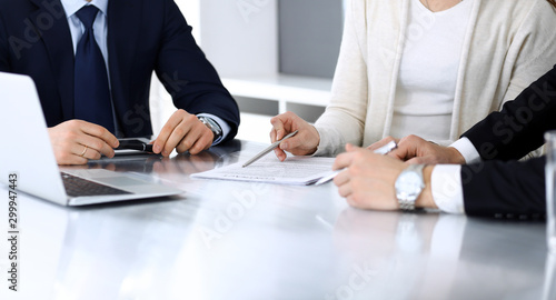 Business people discussing contract working together at meeting at the glass desk in modern office. Unknown businessman and woman with colleagues or lawyers at negotiation. Teamwork and partnership photo
