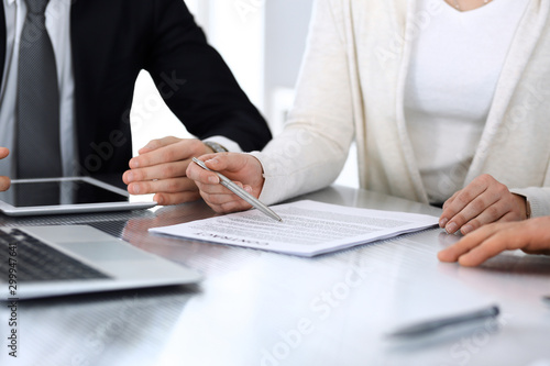 Business people discussing contract working together at meeting at the glass desk in modern office. Unknown businessman and woman with colleagues or lawyers at negotiation. Teamwork and partnership