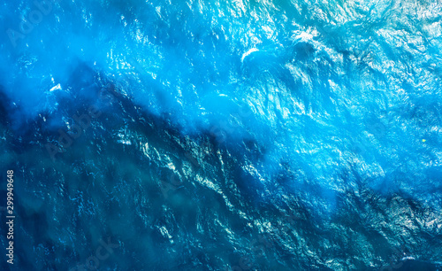 texture of the sea surface with ripples and different shades of turquoise. waves of the turquoise sea with blue layers from the sandy shores, texture view from above with drone
