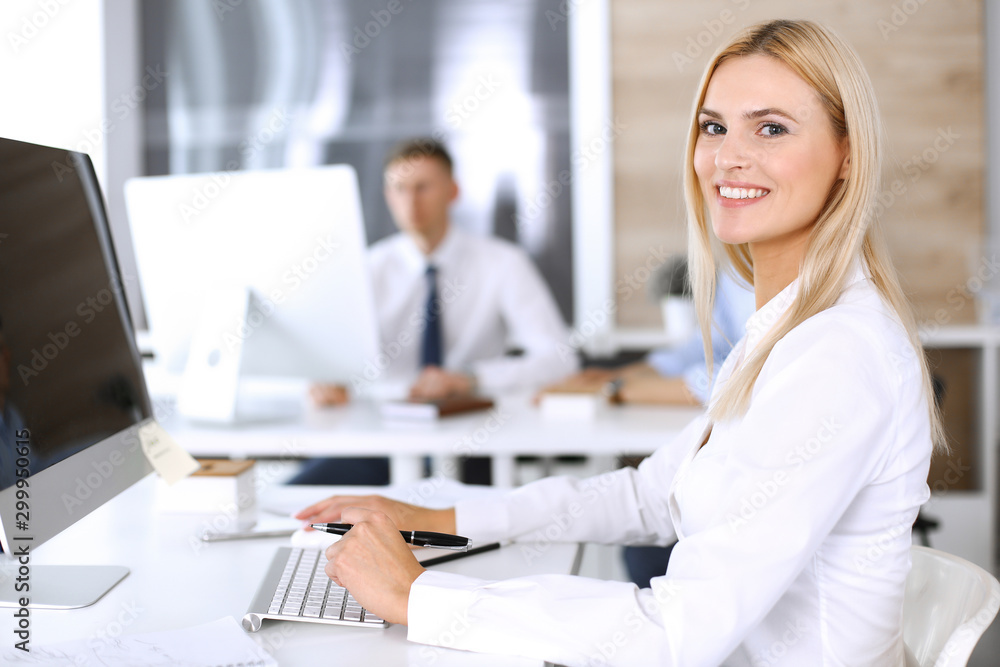 Business woman using computer at workplace in modern office. Secretary or female lawyer smiling and looks happy. Working for pleasure and success Business woman using computer at workplace in modern office. Secretary or female lawyer smiling and looks happy. Working for pleasure and success