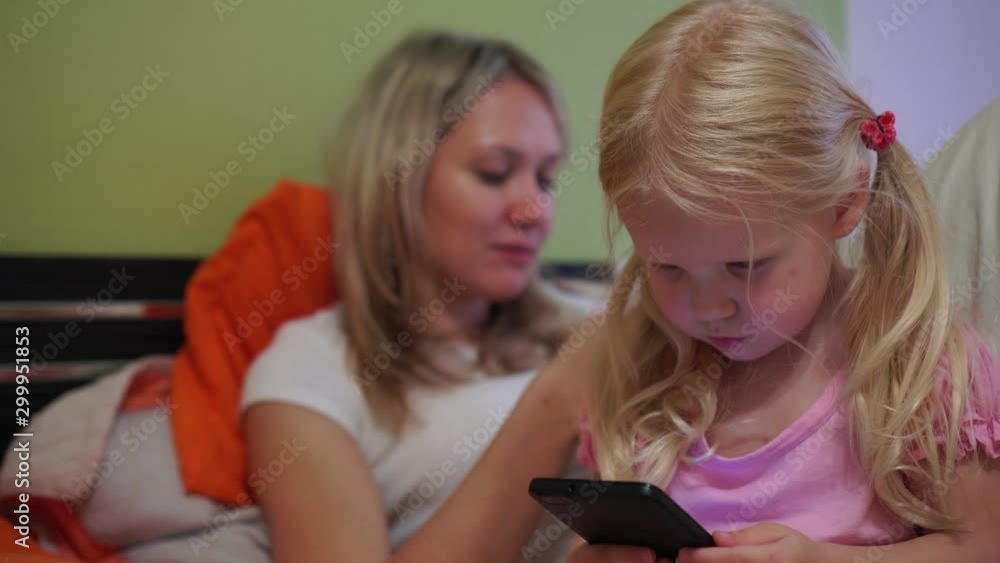 A modern family uses smartphones. Mom with daughter with phones. A modern family uses smartphones. Mom with daughter with phones.
