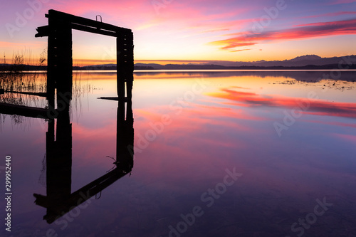 Monte Rosa and the remaining of an old boathouse reflecting on Lake Varese during a winter sunset at Calcinate del Pesce, Varese Province, Lombardy, Italy.
